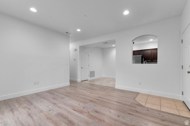 spare room with light wood-style flooring, arched walkways, visible vents, and recessed lighting
