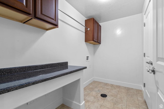 washroom featuring baseboards, light tile patterned floors, a textured ceiling, hookup for a washing machine, and cabinet space