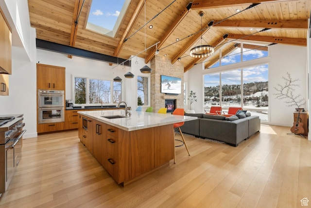 3599 Daybreaker Dr, Park City, UT 84098 - kitchen with brown cabinetry, a stone fireplace, a sink, multiple ovens, and wood ceiling