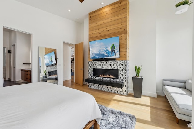 3599 Daybreaker Dr, Park City, UT 84098 - bedroom with recessed lighting, baseboards, a high ceiling, a tiled fireplace, and wood finished floors