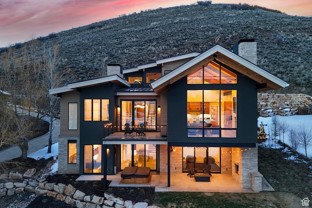 back of house with a chimney, a mountain view, and a patio area