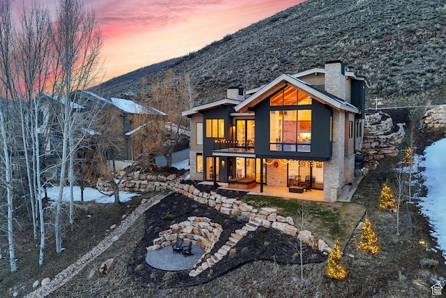 3599 Daybreaker Dr, Park City, UT 84098 - back of house at dusk with a chimney, a patio, and a mountain view