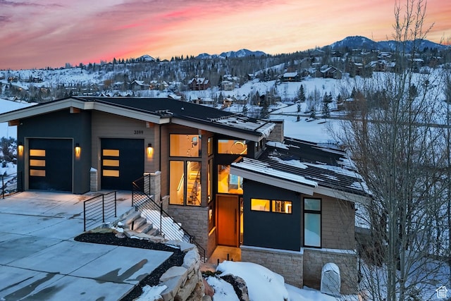3599 Daybreaker Dr, Park City, UT 84098 - contemporary house featuring stone siding, a garage, a mountain view, and concrete driveway
