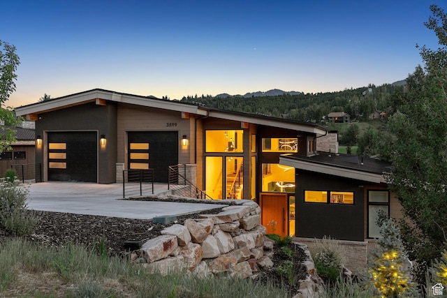 3599 Daybreaker Dr, Park City, UT 84098 - back of property at dusk with an attached garage, driveway, and a mountain view