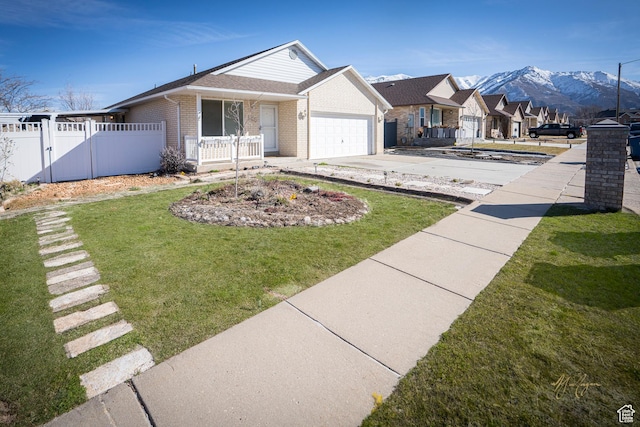 view of front of home with concrete driveway, a front yard, brick siding, a garage, and fence