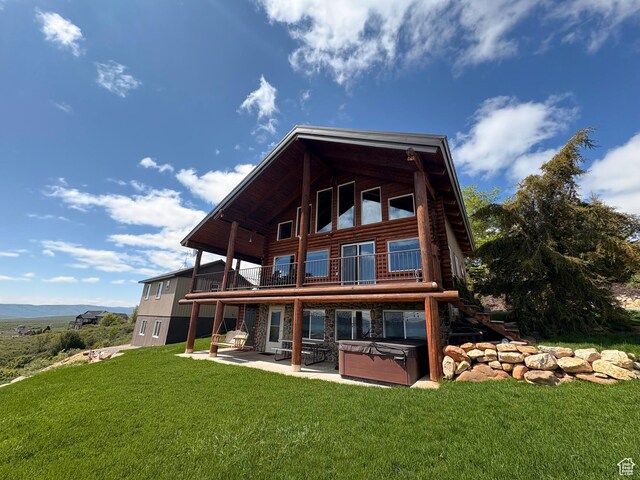 3186 S Sweetwater Pkwy, Garden City, UT 84028 - back of house featuring a hot tub, a patio area, a yard, and a balcony