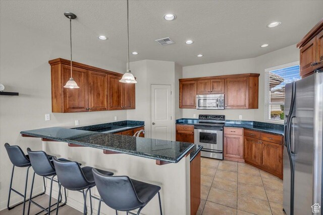 409 N Country Ln Unit 3, St George, UT 84770 - kitchen with visible vents, brown cabinets, a peninsula, and stainless steel appliances