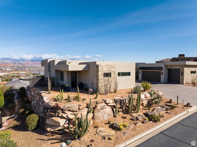 view of front facade featuring stucco siding, a garage, concrete driveway, and a mountain view