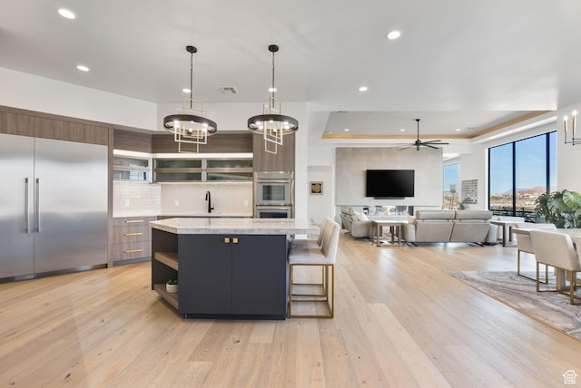 kitchen with light wood-type flooring, open shelves, a sink, a center island, and appliances with stainless steel finishes