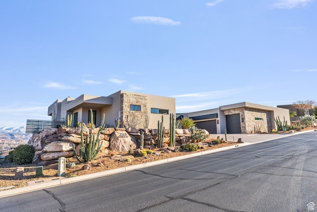 view of front of home featuring stone siding, stucco siding, and a garage