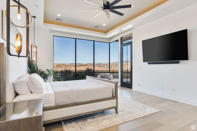 bedroom featuring access to outside, wood finished floors, visible vents, and baseboards