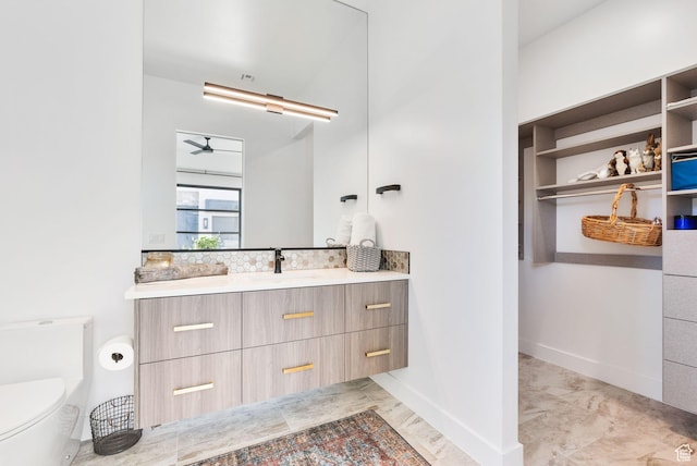 bathroom with vanity, baseboards, ceiling fan, toilet, and marble finish floor