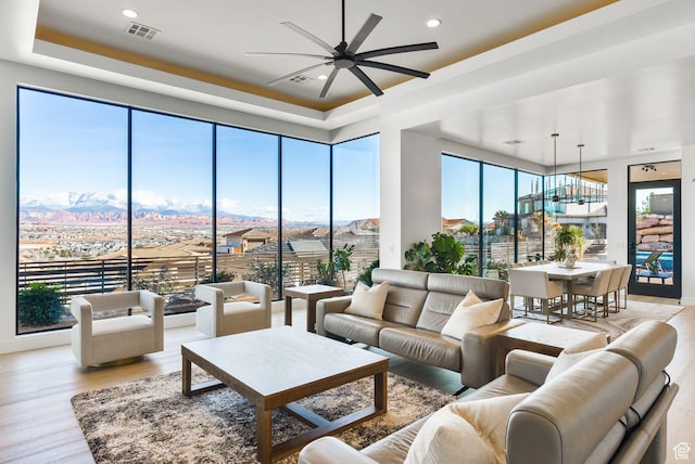 living room featuring visible vents, a ceiling fan, plenty of natural light, a mountain view, and light wood-style floors