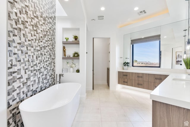 bathroom with tile patterned flooring, visible vents, built in shelves, a freestanding bath, and vanity