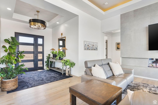 entrance foyer with recessed lighting, a tray ceiling, baseboards, and wood finished floors