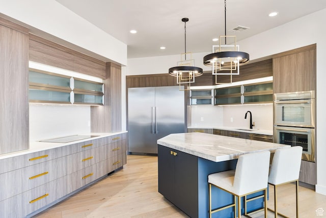 kitchen featuring a kitchen island, appliances with stainless steel finishes, light wood-style floors, modern cabinets, and a sink