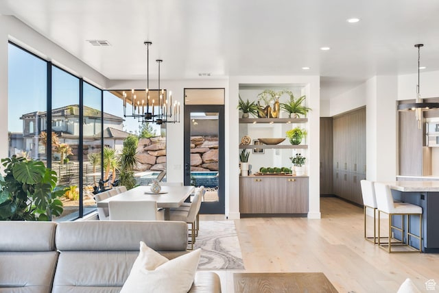 living area with recessed lighting, visible vents, an inviting chandelier, and light wood-style flooring