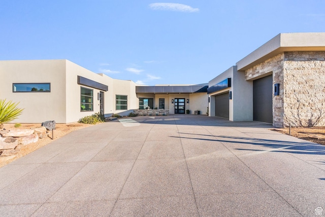 exterior space with stucco siding, a garage, and driveway
