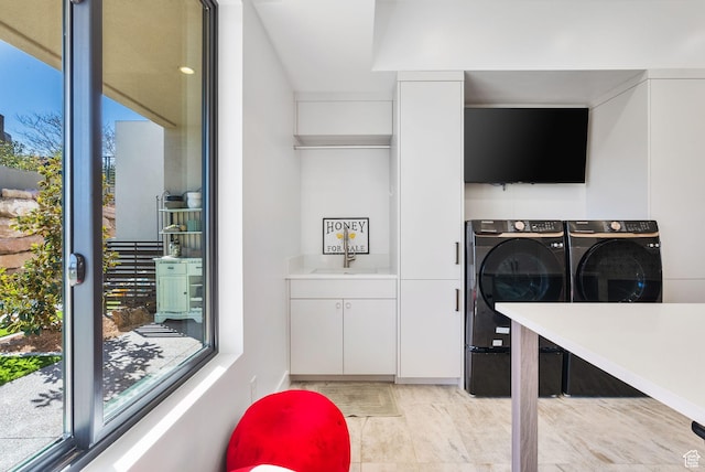 laundry area featuring washing machine and clothes dryer, cabinet space, a wealth of natural light, and a sink