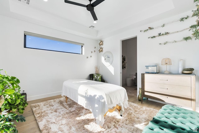 bedroom featuring a raised ceiling, light wood-style flooring, baseboards, and visible vents