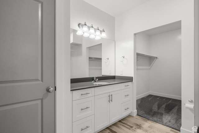 875 S Depot St Unit 344B, Clearfield, UT 84015 - bathroom featuring vanity, a walk in closet, wood finished floors, and baseboards