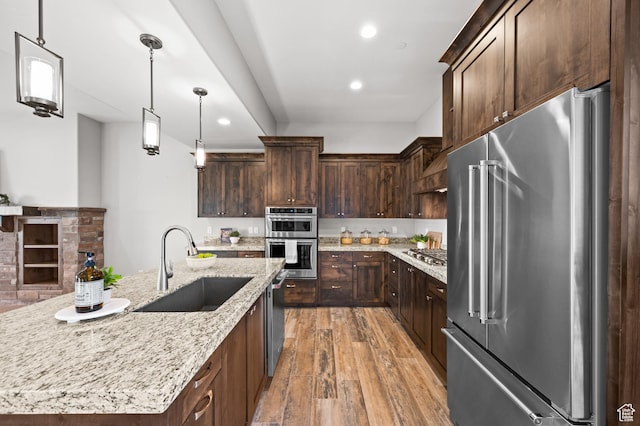 1733 E Viewside Cir, Hideout, UT 84036 - kitchen featuring appliances with stainless steel finishes, a sink, light wood-style flooring, dark brown cabinets, and pendant lighting