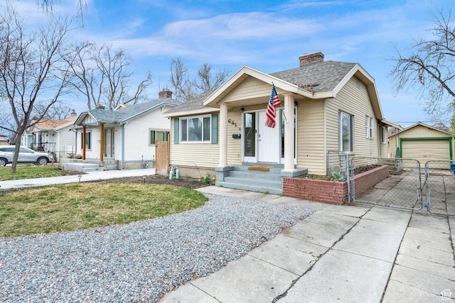 bungalow with an outbuilding, a gate, a chimney, concrete driveway, and a detached garage
