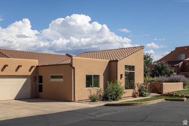 view of front of house with stucco siding, a garage, driveway, and a tiled roof