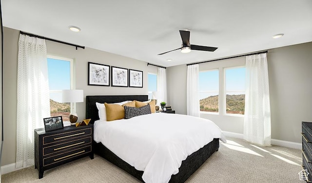 bedroom featuring light colored carpet, baseboards, and ceiling fan