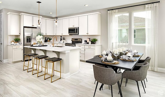 kitchen featuring a sink, stainless steel appliances, a breakfast bar area, and decorative backsplash