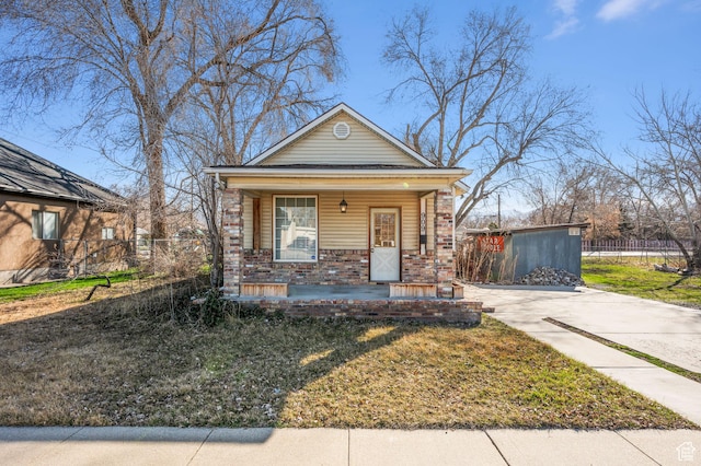 909 S Concord St, Salt Lake City, UT 84104 - shotgun-style home featuring a front lawn, a porch, fence, concrete driveway, and brick siding