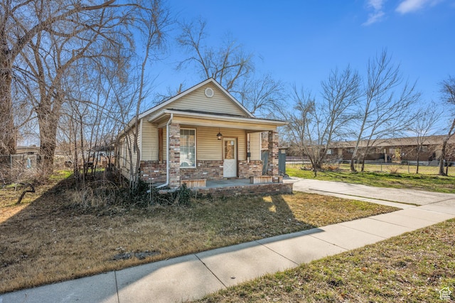 909 S Concord St, Salt Lake City, UT 84104 - view of front facade with driveway, fence, covered porch, a front yard, and brick siding