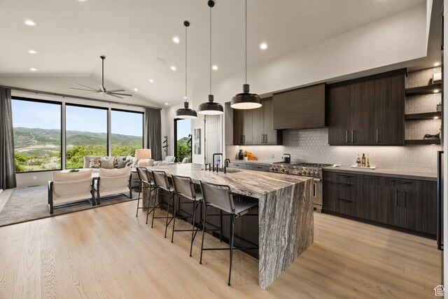 11503 N Soaring Hawk Ln, Hideout, UT 84036 - kitchen featuring high end stove, open shelves, wall chimney range hood, a kitchen breakfast bar, and modern cabinets