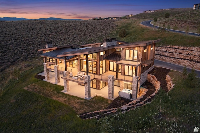 6421 E Evening Star Dr, Kamas, UT 84036 - back of property at dusk with a patio area, a chimney, a standing seam roof, and metal roof