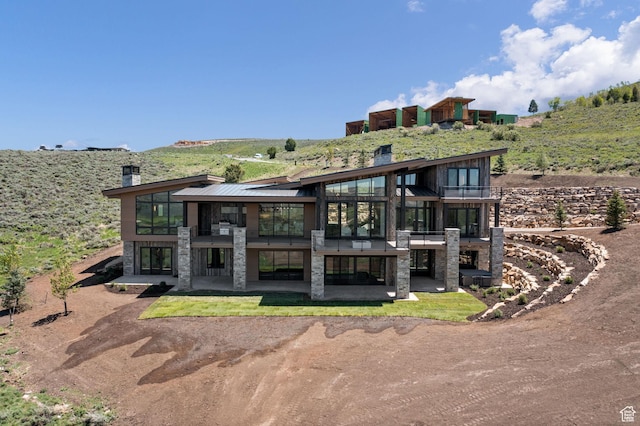 6421 E Evening Star Dr, Kamas, UT 84036 - rear view of house with stone siding, a patio, a chimney, and a balcony