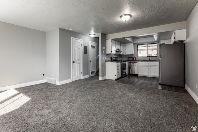 1325 S Lincoln Ave Unit 19, Ogden, UT 84404 - kitchen featuring under cabinet range hood, dark countertops, dark carpet, stainless steel appliances, and white cabinets