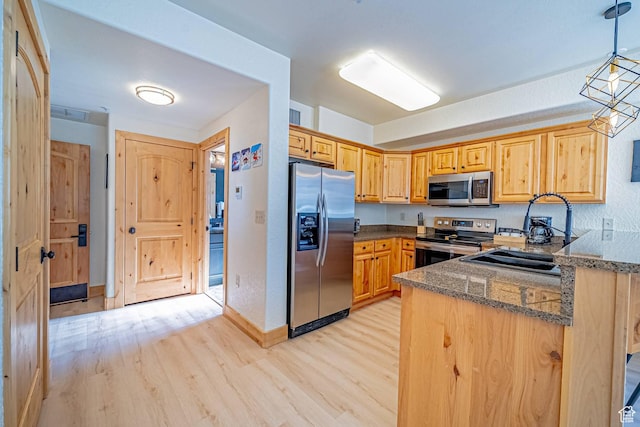 2669 Canyons Resort Dr Unit 314, Park City, UT 84098 - kitchen featuring dark stone counters, a sink, hanging light fixtures, light wood-style floors, and appliances with stainless steel finishes