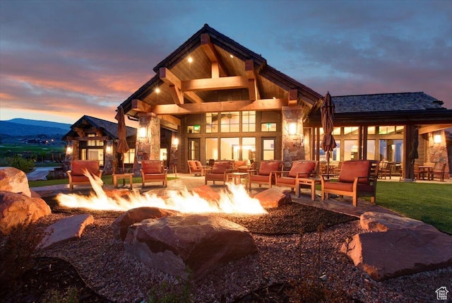 1878 E Chimney Rock Rd S Unit 536, Heber City, UT 84032 - back of house at dusk featuring stone siding, an outdoor living space with a fire pit, and a patio