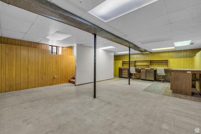 below grade area with carpet flooring, wood walls, a bar, and stairs