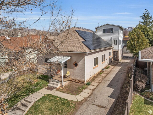view of front of home featuring solar panels, fence, brick siding, and roof with shingles