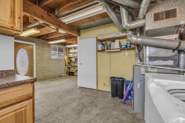 basement featuring visible vents, washer / dryer, and concrete block wall