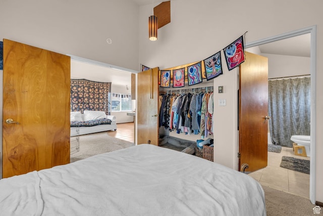 carpeted bedroom featuring a closet, connected bathroom, a towering ceiling, and tile patterned flooring