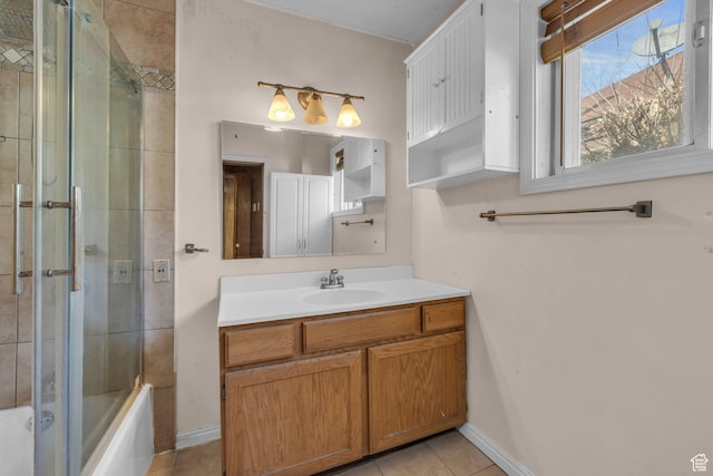 bathroom featuring tile patterned floors, vanity, baseboards, and shower / bath combination with glass door