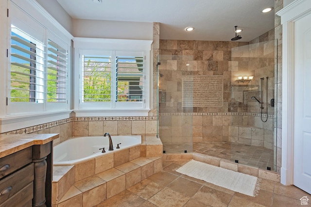 bathroom featuring stone tile floors, a bath, a shower stall, and recessed lighting