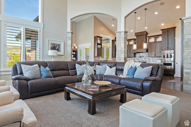 living area with arched walkways, decorative columns, a high ceiling, and recessed lighting