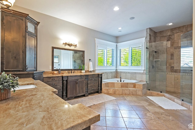 full bath with a stall shower, a garden tub, two vanities, recessed lighting, and stone tile flooring
