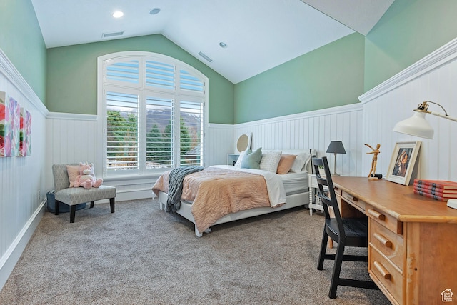 carpeted bedroom featuring a wainscoted wall, lofted ceiling, and a desk