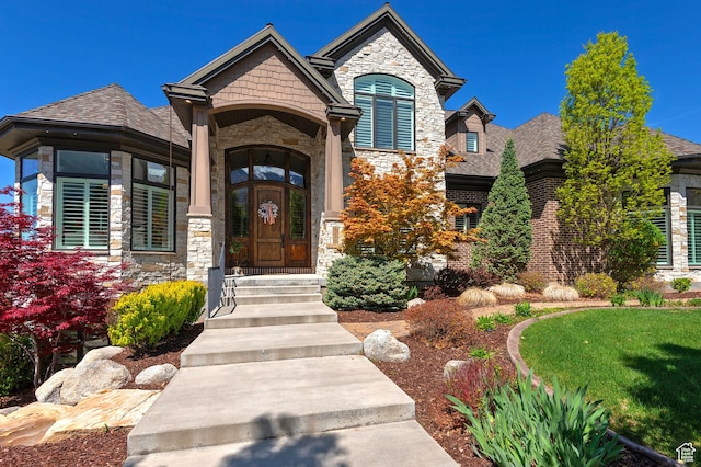 view of front facade featuring stone siding and a shingled roof