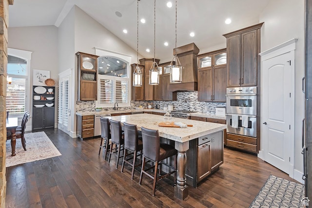 kitchen with appliances with stainless steel finishes, a center island, decorative backsplash, high vaulted ceiling, and a kitchen bar