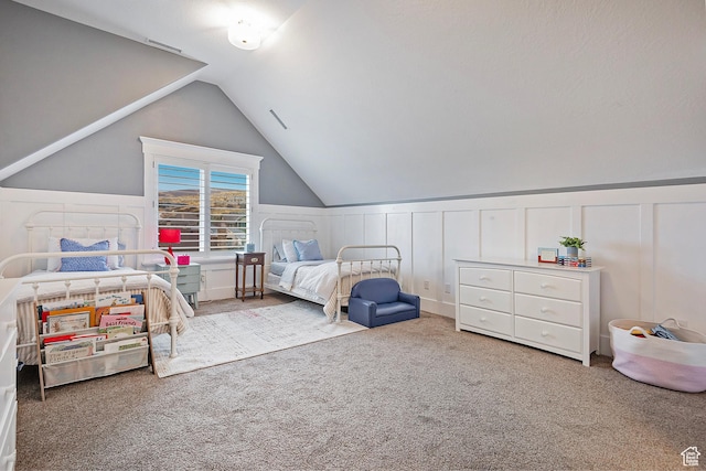 bedroom with a decorative wall, carpet flooring, lofted ceiling, and a wainscoted wall